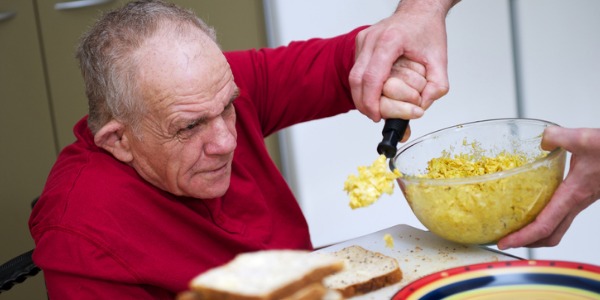 Occupational therapist helping a man eat after a stroke.